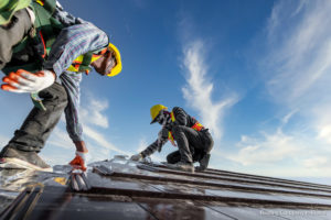 Two male workers wearing safety clothes Installing the roof tile