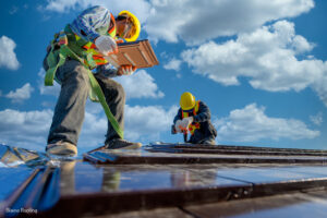 Two male workers wearing safety clothes Installing the roof tile