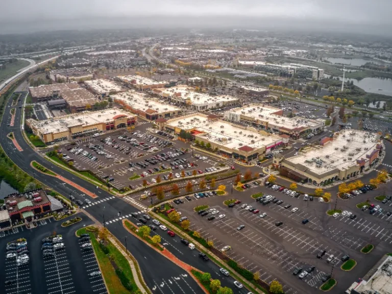 Aerial view of a large shopping center with multiple buildings and parking lots on a cloudy day.