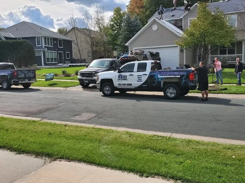 Workers and trucks outside a house with people repairing the roof.