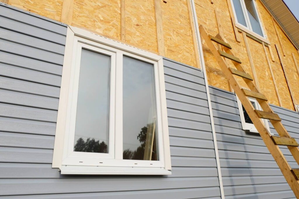House exterior under construction with siding, windows, and a wooden ladder.