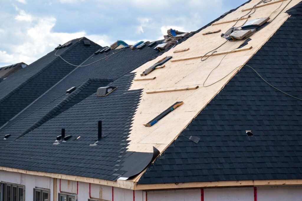 A roof partially covered with black shingles during installation on a house under construction.