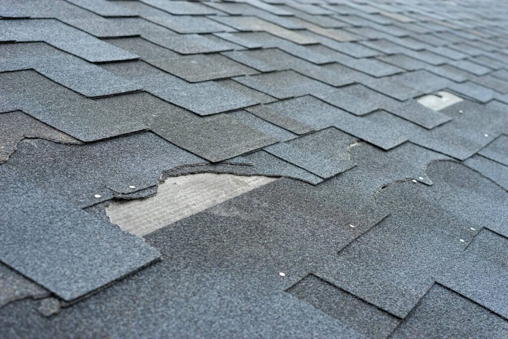 Worn and damaged asphalt roof shingles with some missing pieces.